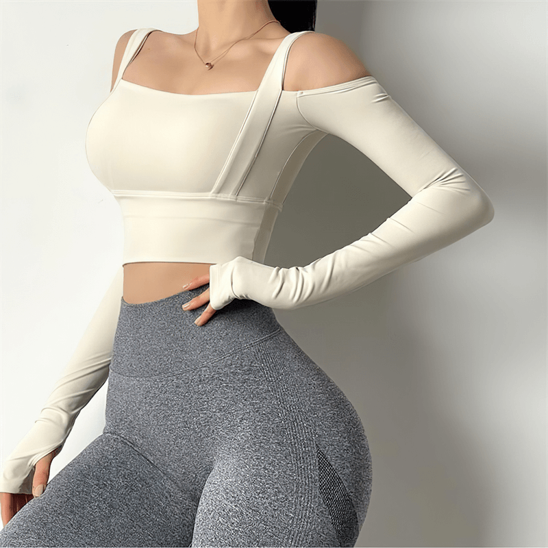 Stylish women's cream crop top with open shoulders and long sleeves, paired with gray leggings, perfect for gym and active wear.