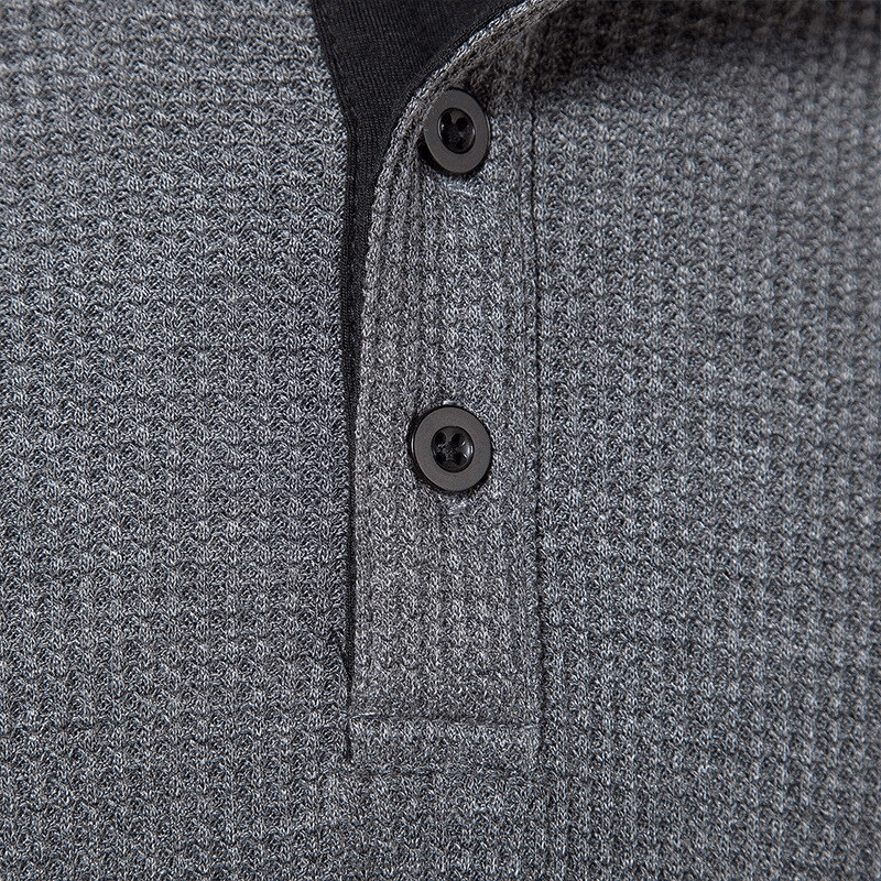 Close-up of a textured grey shirt with black buttons, showcasing intricate fabric detail.