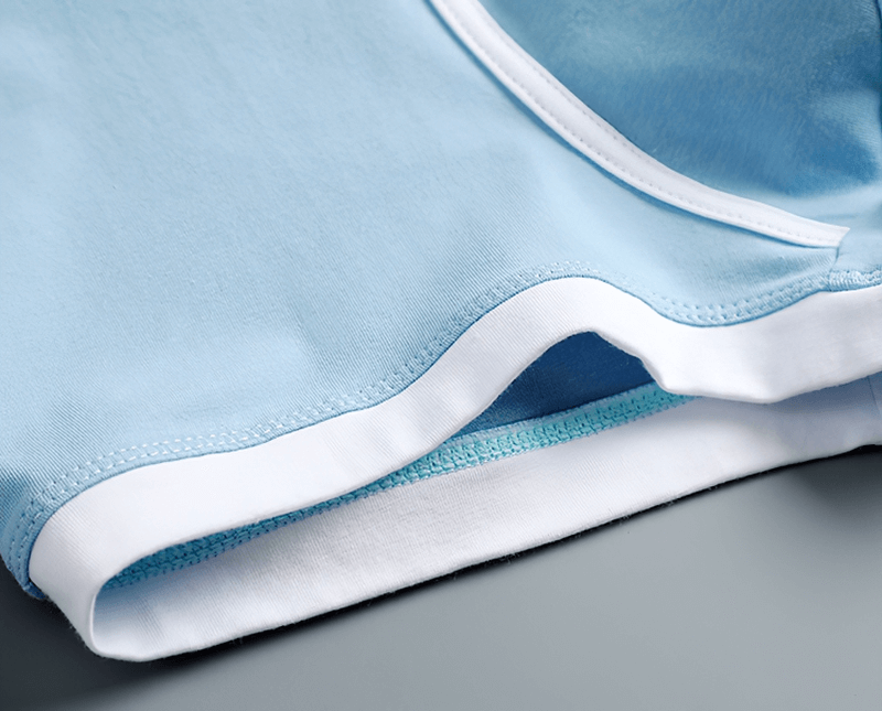 Close-up of light blue cotton boxer shorts for men with white trim, showcasing comfort and quality stitching.