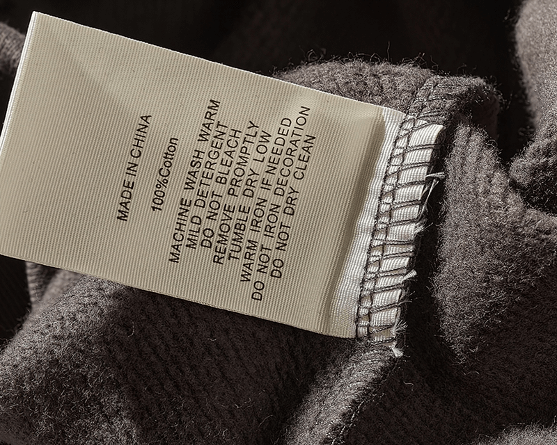 Care label on solid color sweatshirt, detailing washing and fabric instructions.
