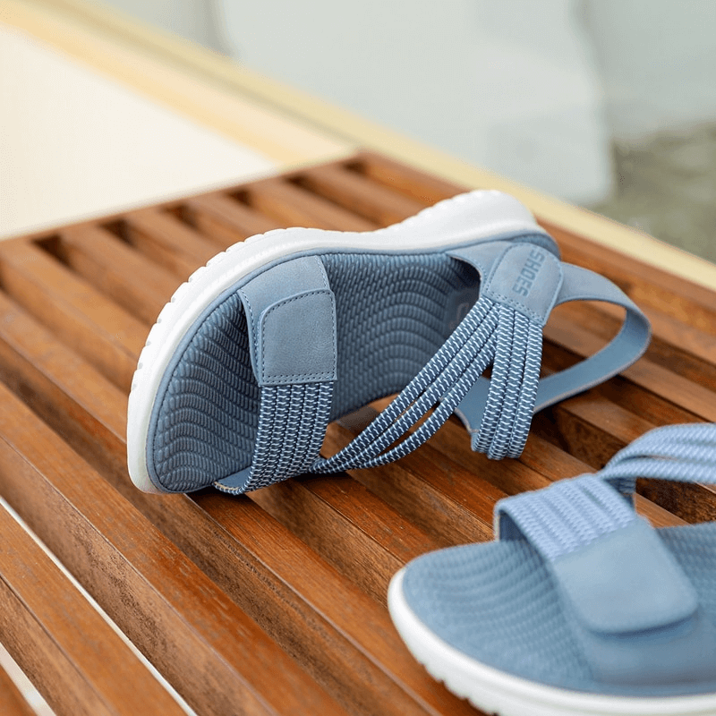 Blue sport women's soft sandals with Velcro straps on a wooden surface.