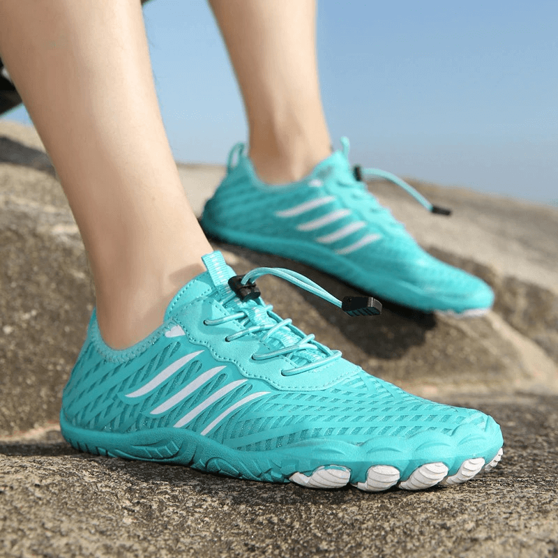 Turquoise sports sneakers with drainage holes and anti-slip soles, perfect for an active lifestyle. SF0571 model displayed on rocky terrain.