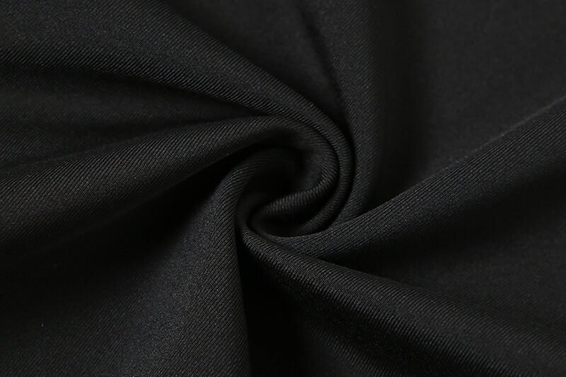 Close-up of black polyester and spandex fabric with a slightly stretchable texture for sports asymmetrical elastic romper.