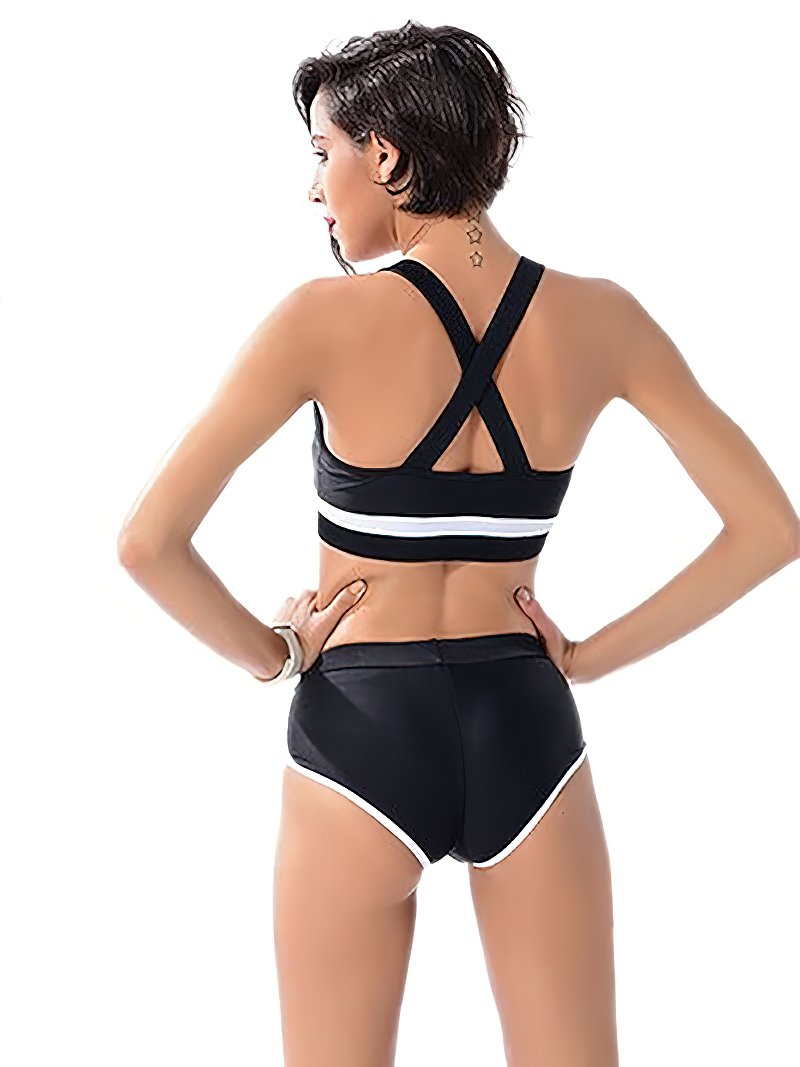 Sporty black and white women's two-piece swimsuit with a strappy back design and short trunks, perfect for a stylish beach day.