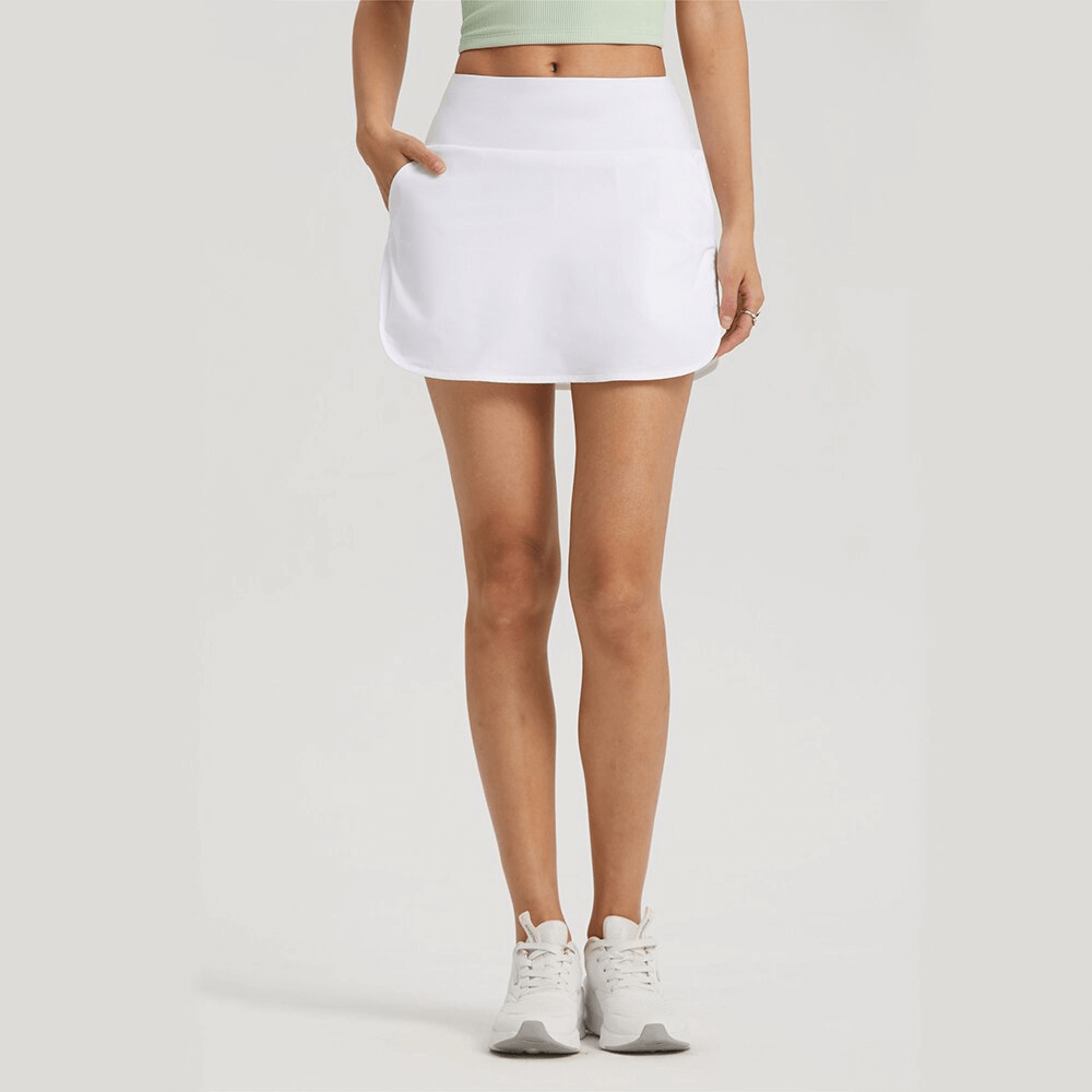 Woman wearing white sports elastic skirt-shorts for tennis, showcasing comfort and mobility. Perfect for intense play - SF1256.