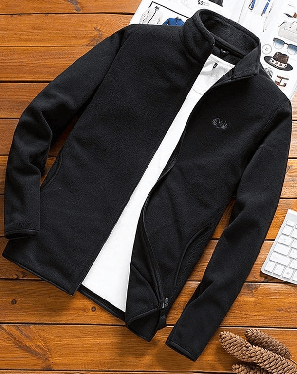 Black sports fleece men's zip-up jacket with side pockets, lying open on a wooden surface.