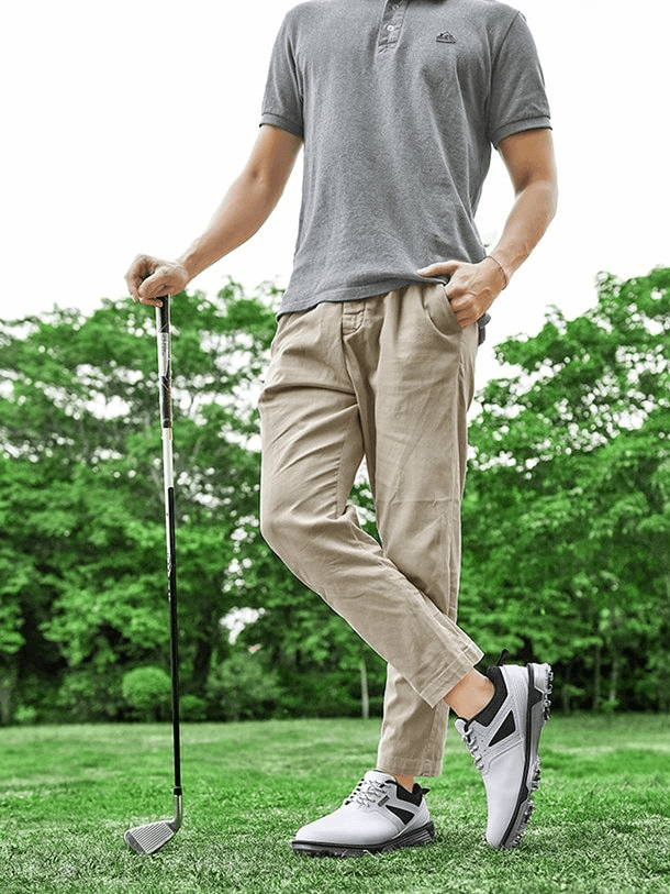 Man wearing Sports Flexible Non-Slip Men's Sneakers / Golf Shoes SF1175 holding a golf club on a lush green course.