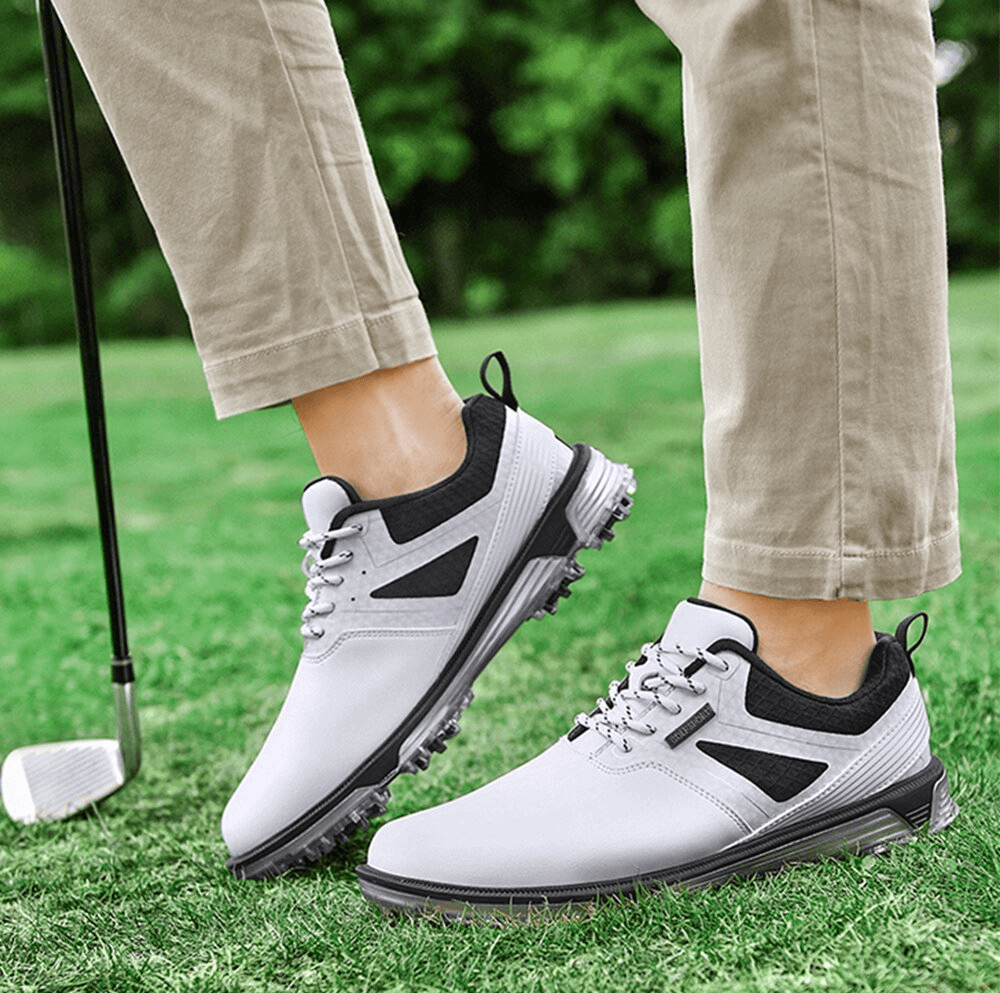 Man wearing flexible non-slip men's sneakers, perfect for golf, on green grass with a golf club nearby.