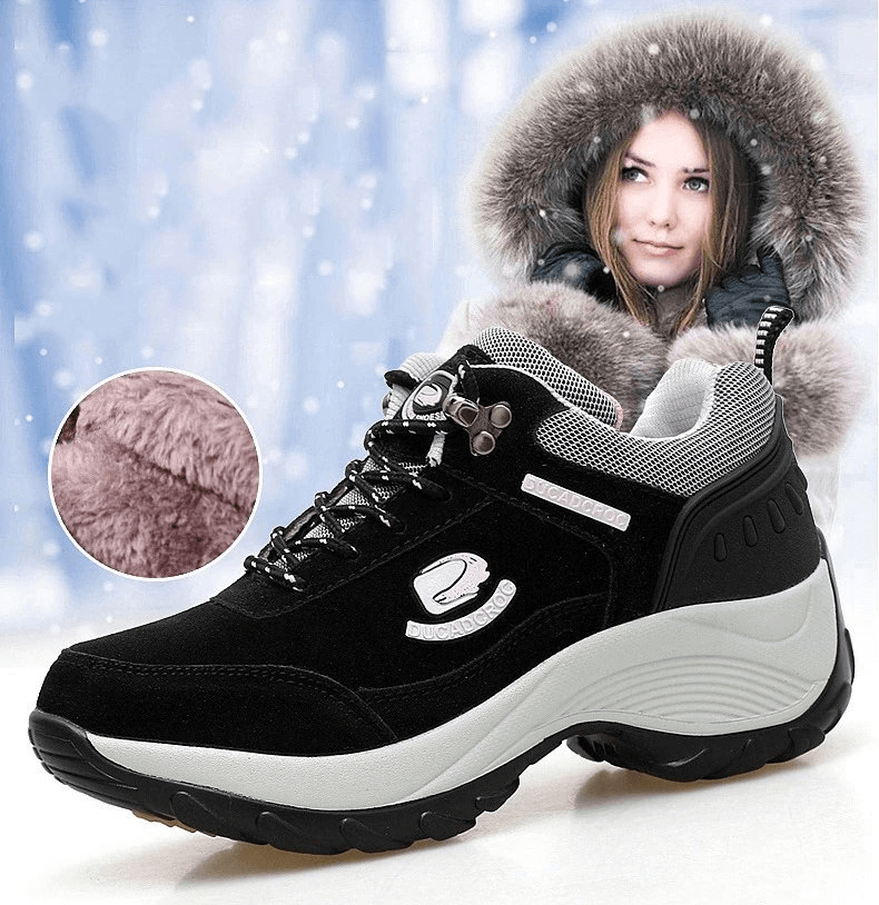 Women's insulated sports shoes, featuring black suede and faux fur, perfect for winter style. Model with fur hood in snowy setting.