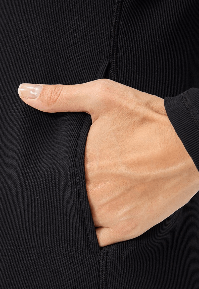 Close-up of hand in pocket of sports insulated women's jacket, showcasing black fleece fabric and thumb hole style.