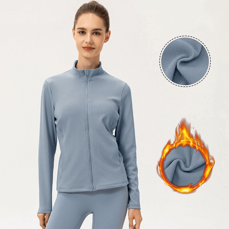 Sporty women's jacket with fleece-lined zipper for warmth, thumb holes, and high collar. Perfect for athletic activities. Model shown wearing jacket.