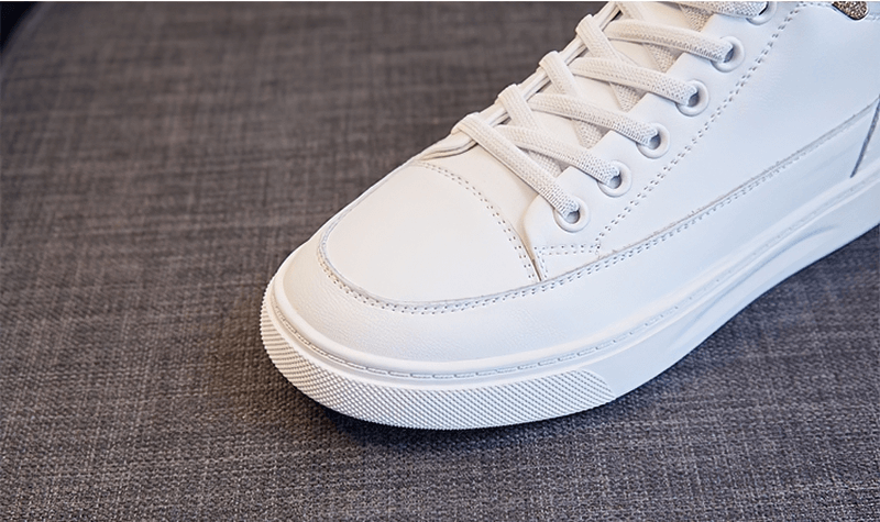 Close-up of white sports lace-up genuine leather shoe for women on gray surface