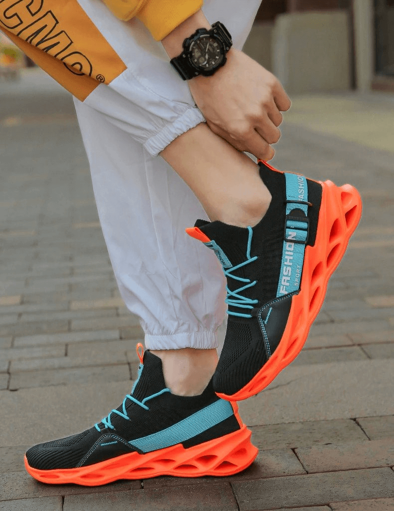 Bright neon orange and black athletic sneakers with breathable mesh design on male feet.