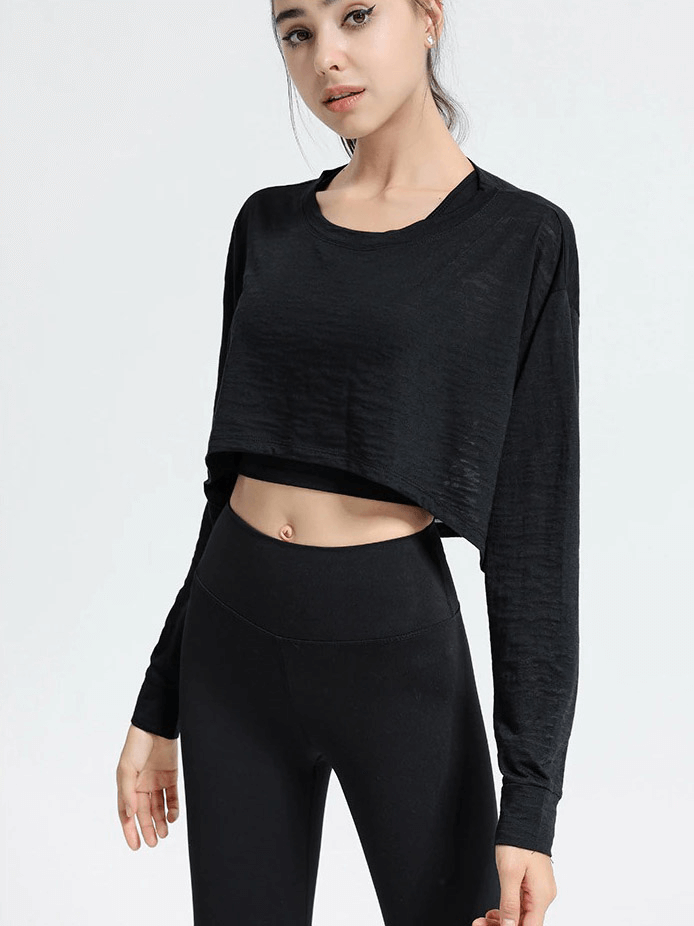Woman wearing a black long-sleeved loose top, ideal for fitness activities like yoga, gym, and aerobics, made from breathable cotton-polyester.