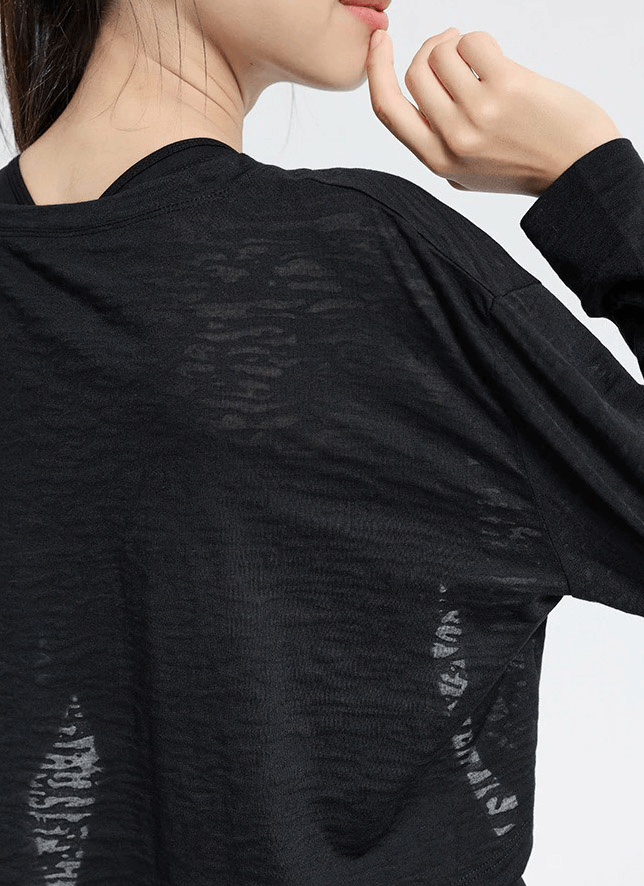 Woman wearing black sports long-sleeved loose top, perfect for fitness and yoga, showcasing breathable cotton-polyester material.