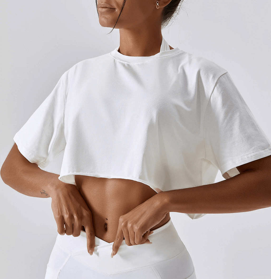 Woman wearing a white sports loose crop top, perfect for yoga, running, or training, featuring an O-neck and breathable fabric.