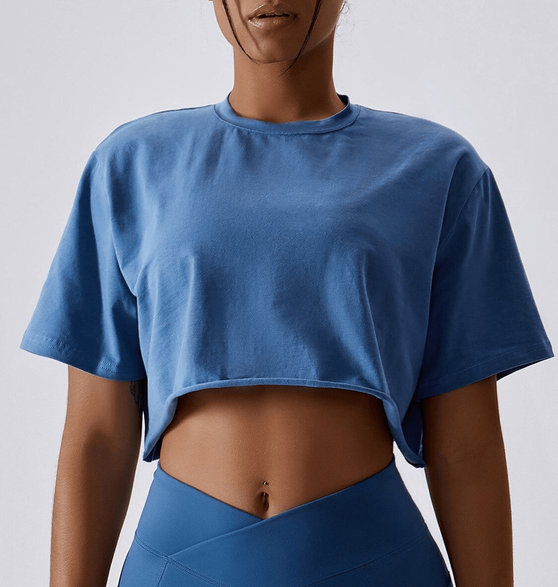 Woman wearing blue sports loose crop top, O-neck style, ideal for yoga, running, or training. Breathable and stylish activewear.