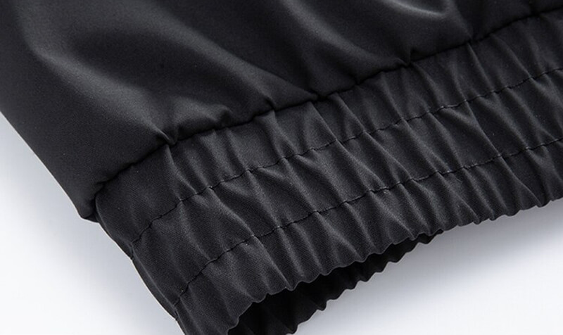 Close-up of black sports men's hooded jacket with elastic cuff, made from durable polyester, featuring sleek design and reflective strips.