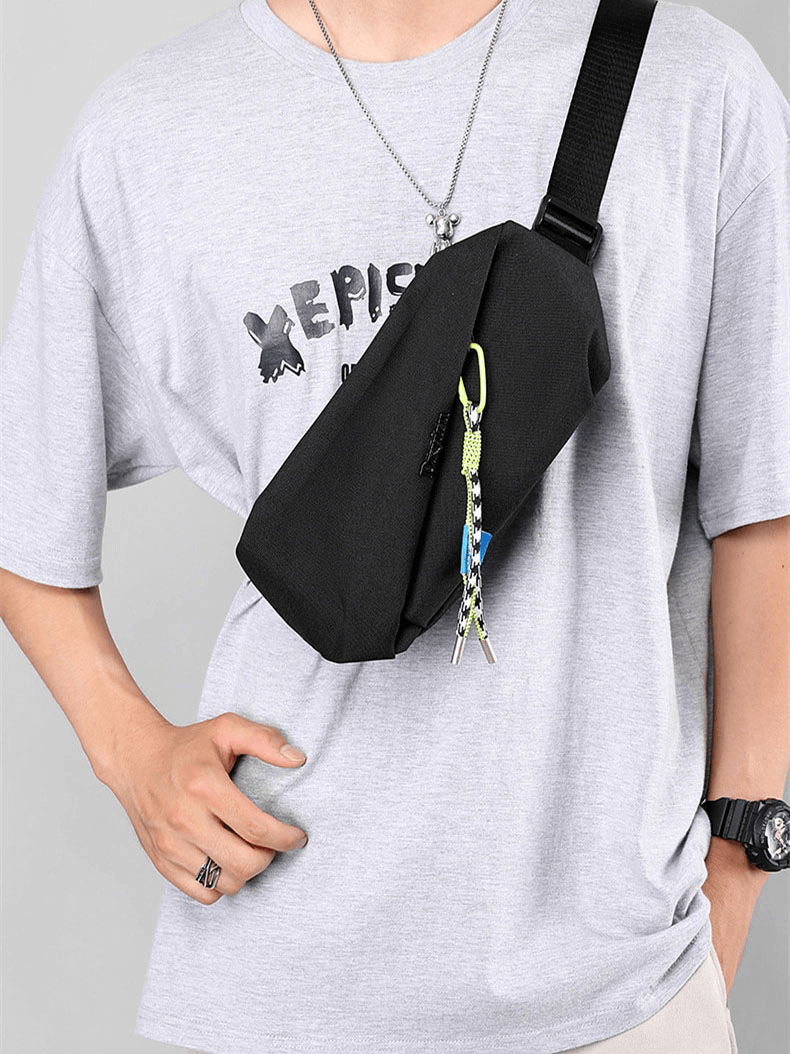 Man wearing a black men's waterproof crossbody chest bag with a removable pendant and tassel decoration.