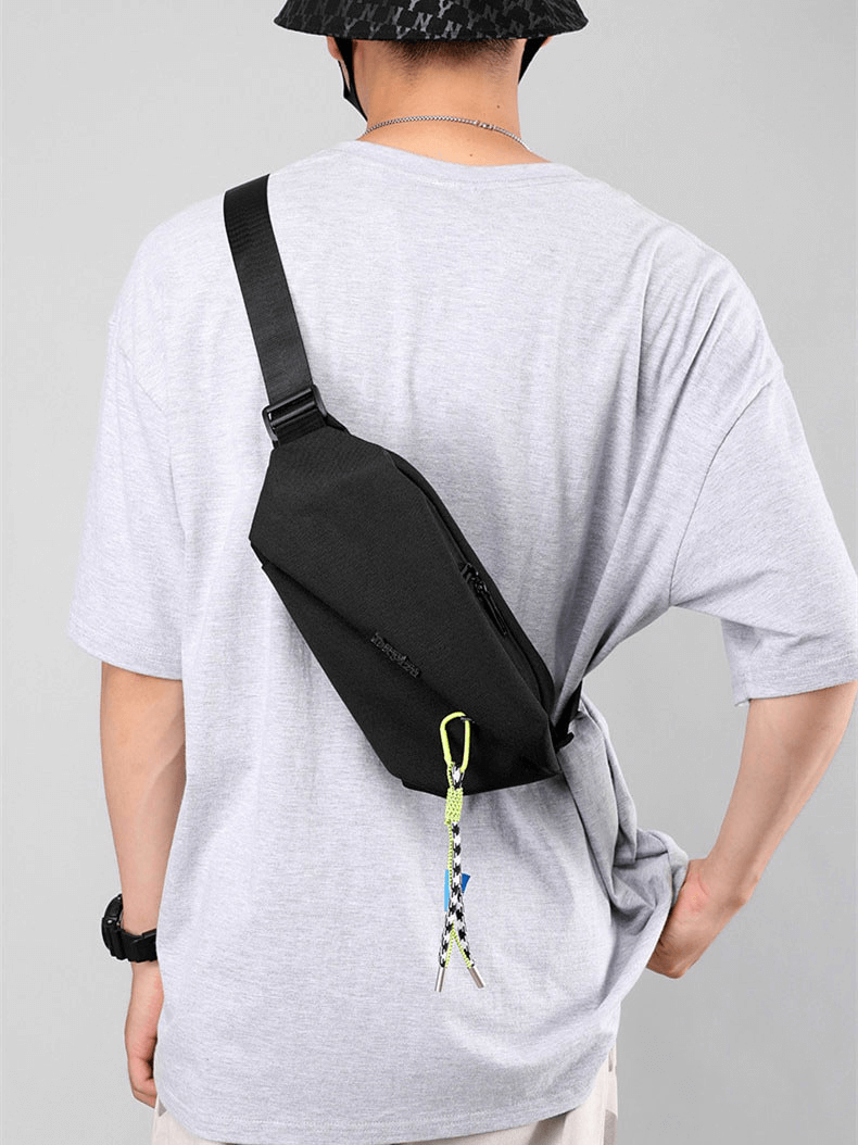 Man wearing black waterproof crossbody bag with removable pendant, showcasing stylish panelled design and tassel decoration.