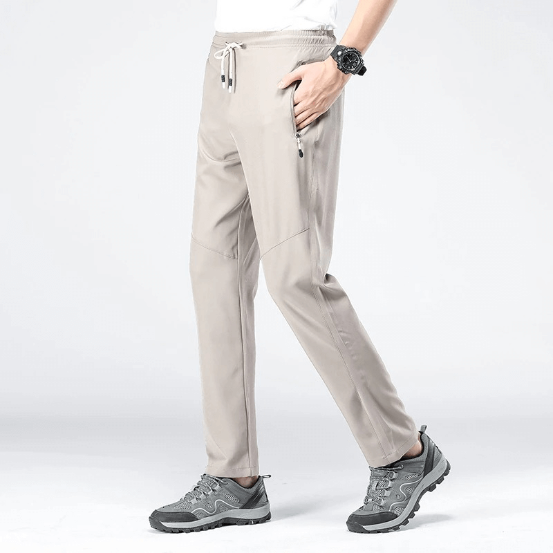 Model wearing beige sports quick-drying men's pants with pockets, perfect for hiking and camping, featuring elastic waist and lightweight design.