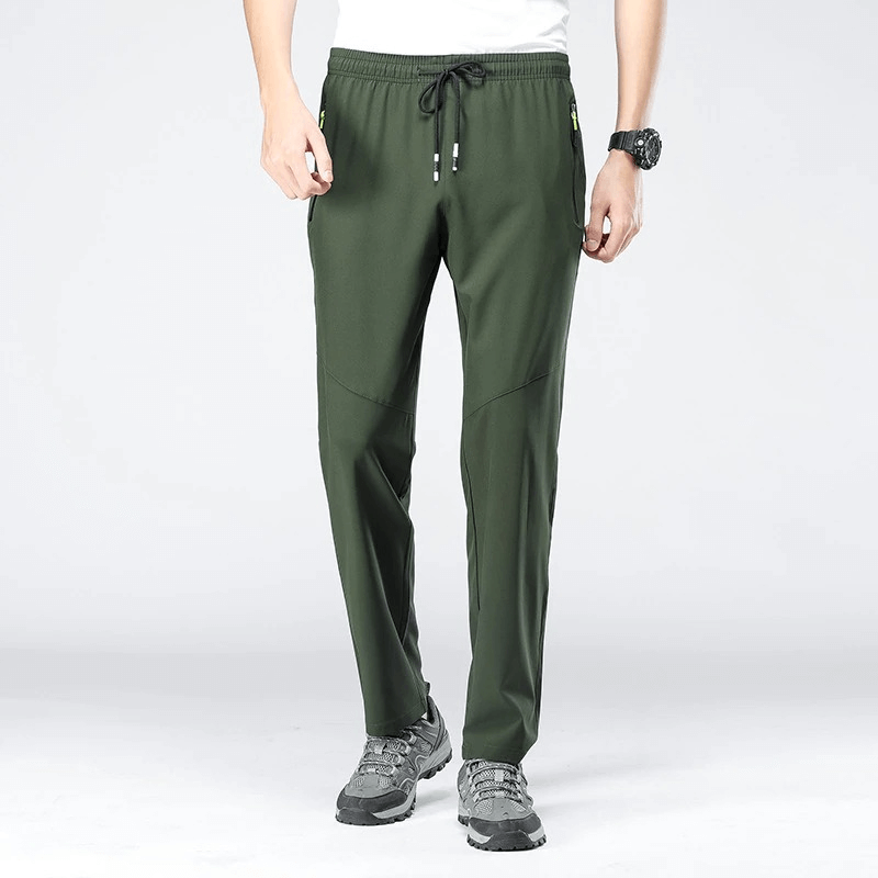 Man wearing green sports quick-drying pants with an elastic waist, perfect for hiking or camping. Features convenient pockets. Full length.