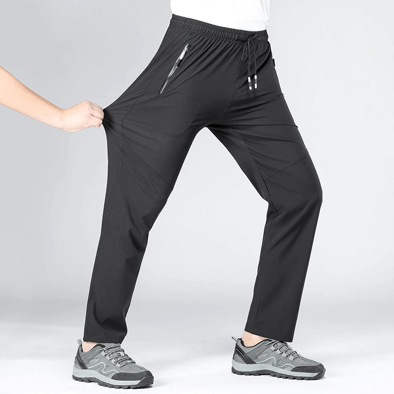 Person wearing black sports quick-drying men's pants with pockets, showcasing stretchy material and comfortable fit while hiking.