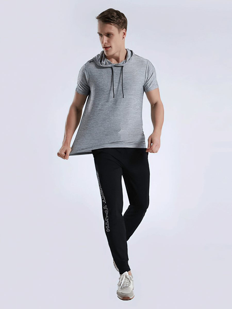 Man wearing sports running quick-dry T-shirt with hood and black pants, demonstrating comfortable workout sportswear.