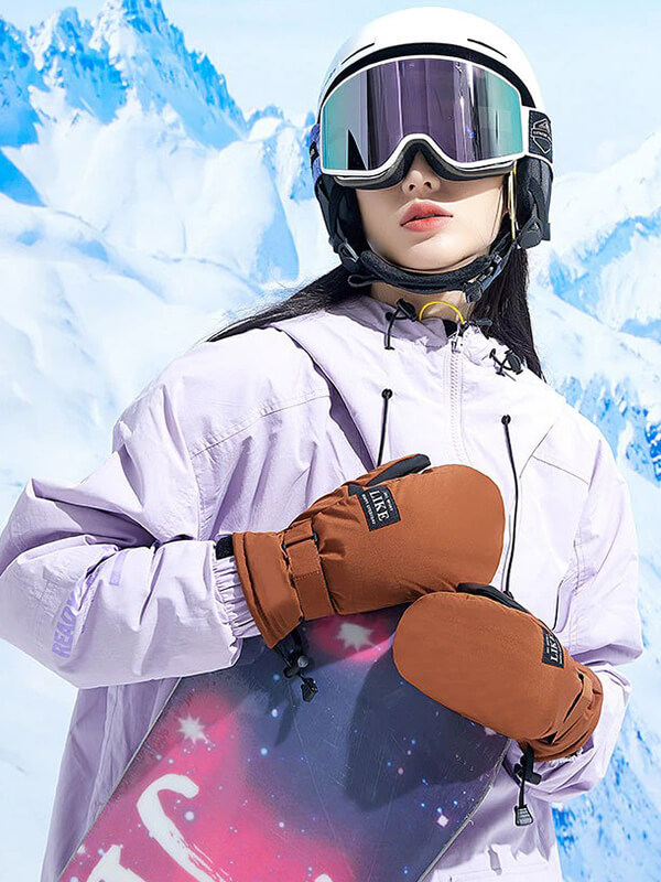 Skiing woman with touch screen gloves holding snowboard, wearing helmet and goggles in snowy mountains.