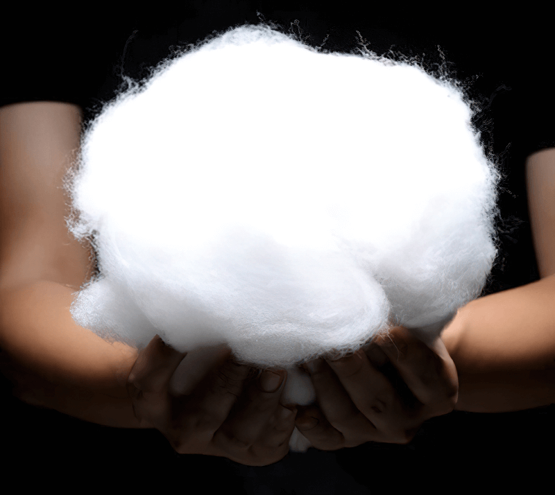 Hands holding fluffy, cloud-like material against a dark background, representing softness and comfort.