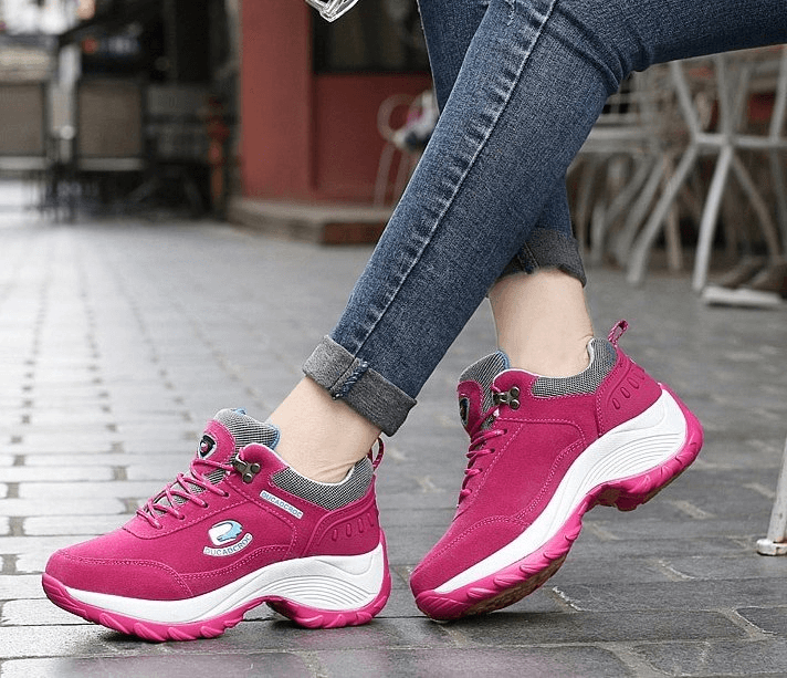 Woman wearing stylish pink sports sneakers with animal print, featuring suede uppers and lace-up design for comfort and stability.
