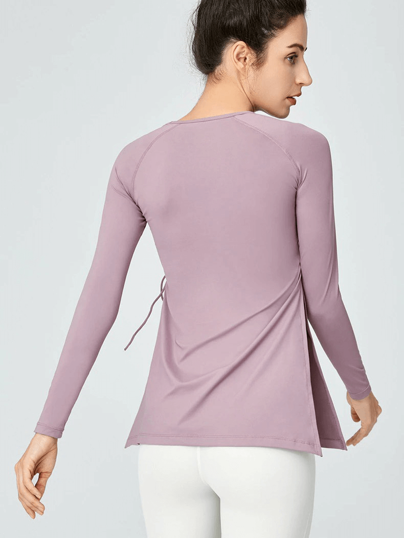 Back view of a woman wearing a mauve sports waist drawstring top with slits, paired with white leggings, showcasing fitness fashion.