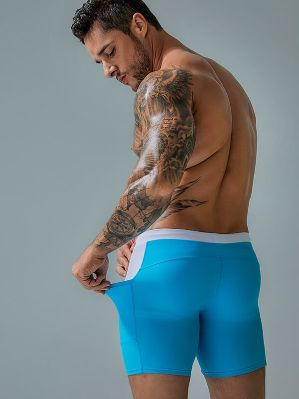 A man adjusting the drawstring on bright blue waterproof beach boxer shorts with pockets, showcasing their fit and style.