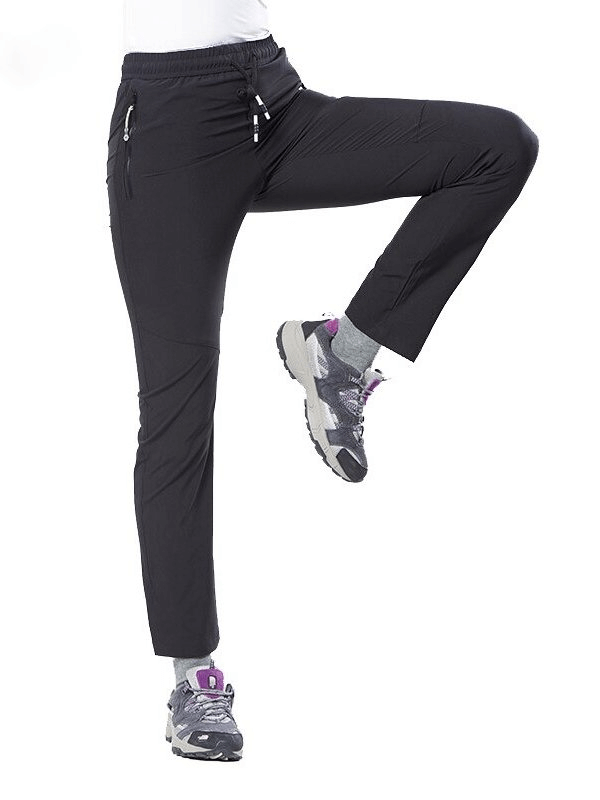 Women's waterproof hiking pants in black, featuring pockets, elastic waistband, and quick-dry material for outdoor sports activities like trekking.