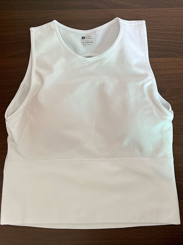 White women's backless short tank top for pilates, made of breathable spandex and nylon. Ideal for yoga and casual wear.