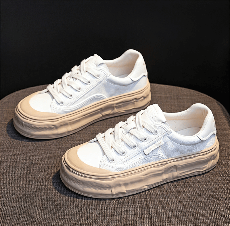 White lace-up women's sneakers with thick soles on gray fabric, offering comfort and style for active wear.