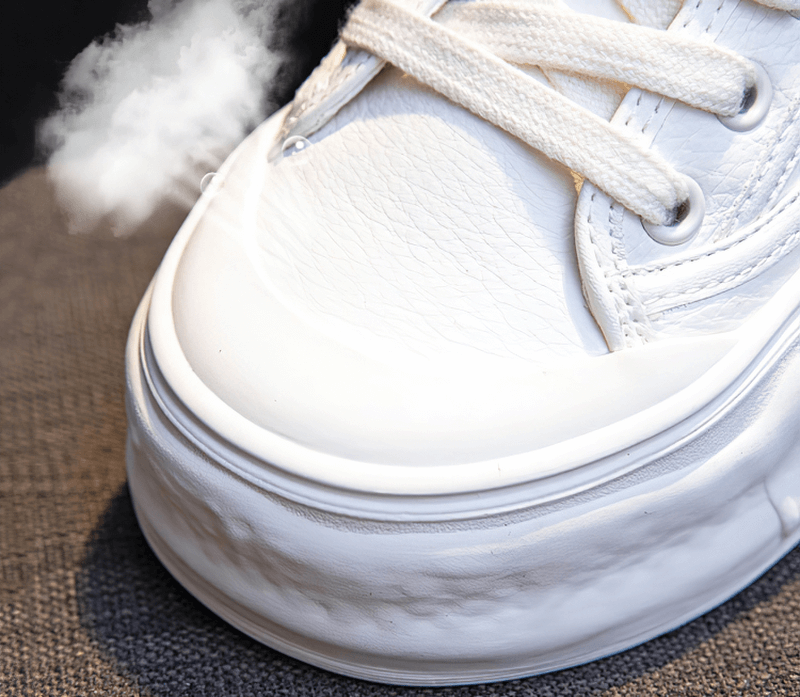 Close-up of white sports women's round toe sneaker with thick sole, showing steam for comfort and cushioning.