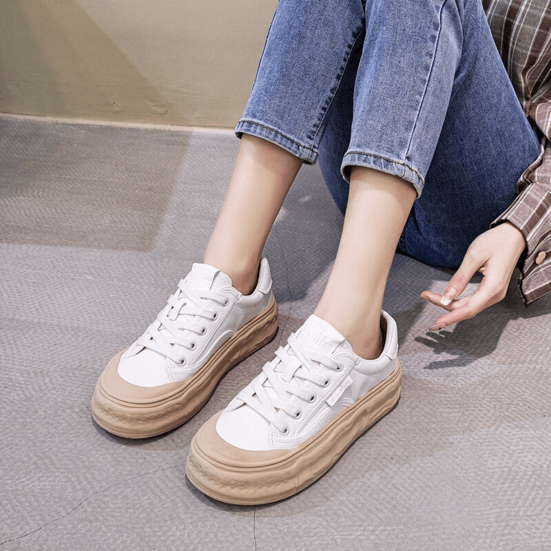 Woman wearing white lace-up sneakers with thick sole, paired with blue jeans, showing style and comfort.