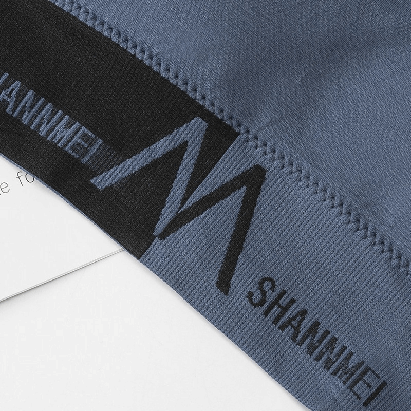 Close-up of blue seamless bra top with black band and "SHANNMEI" lettering, designed for comfort and performance in sports activities.