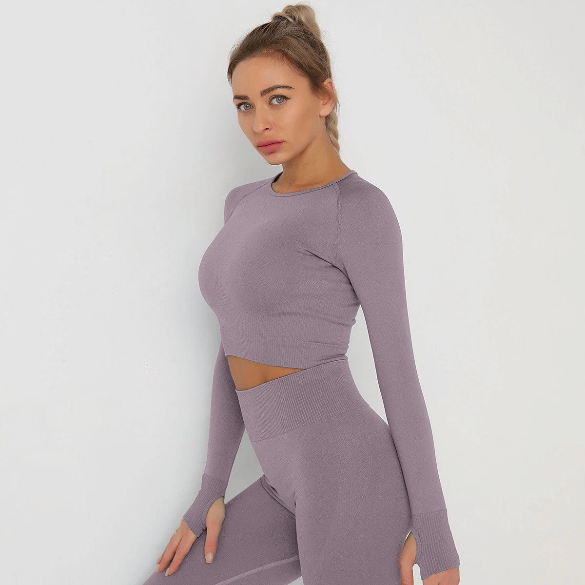 Model wearing a purple long sleeve crop top, showcasing breathable and quick-dry fabric, perfect for yoga and gym fashion.