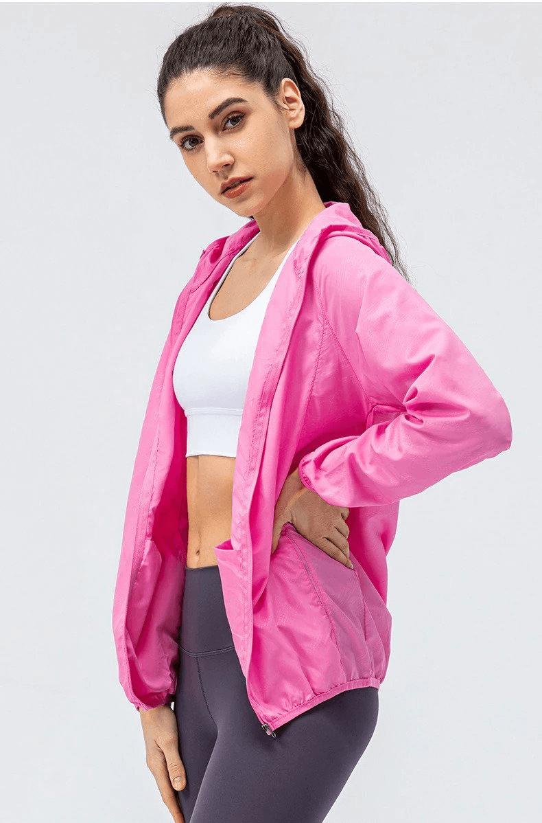 Woman wearing pink waterproof windbreaker jacket with hood, designed for running, showcasing sporty style and functionality.