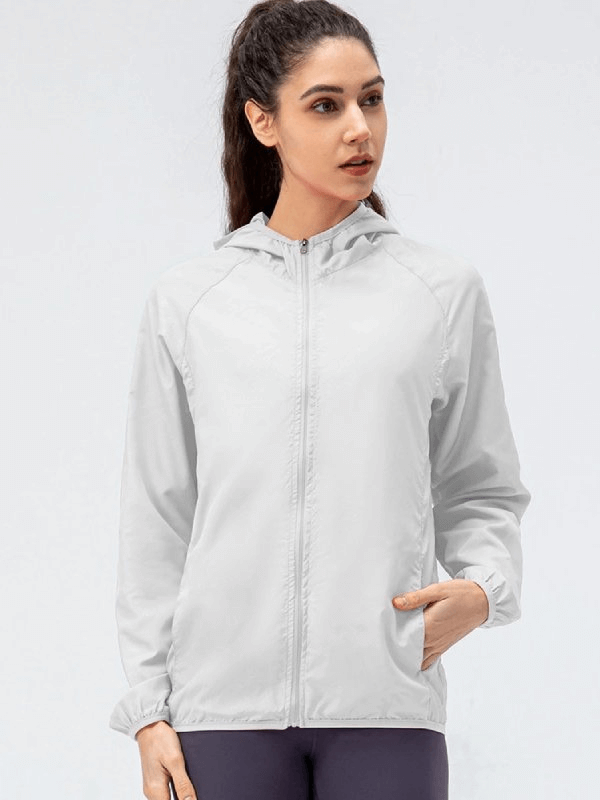 Woman wearing a white sports waterproof windbreaker with hood, perfect for running; features a full-length zipper and breathable polyester material.