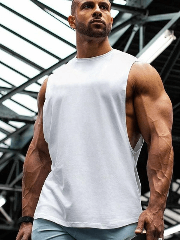 Man wearing a sporty, quick-drying men's tank with dropped armholes, ideal for training and sports, in an industrial setting.