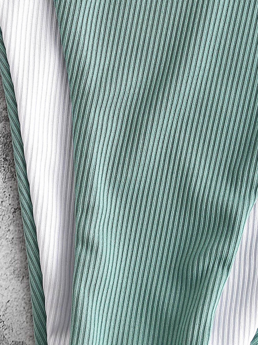 Close-up of green and white ribbed fabric on swimwear for women, showing texture and quality.