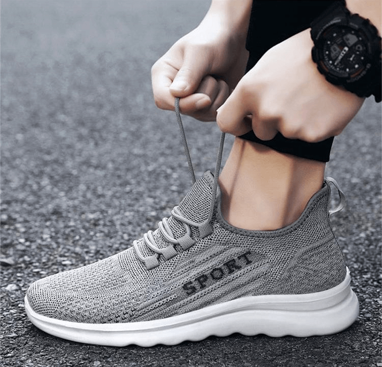 Man tying laces of stylish breathable elastic lace-up sneakers, mesh upper, perfect for comfort and fashion on the go.