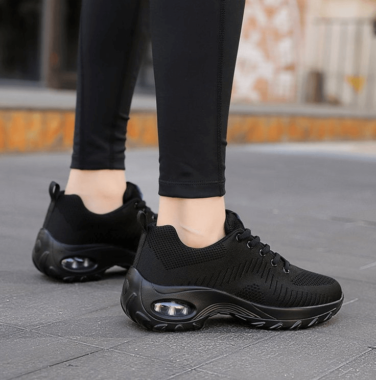 Woman wearing black stylish breathable flexible women's sneakers SF0775 during outdoor walk, highlighting mesh upper and non-slip sole.