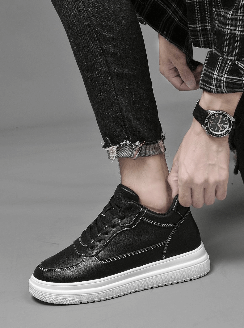 Person tying black unisex high-top sneakers with breathable leather uppers and white rubber soles, paired with black jeans.