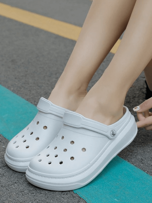 Person wearing stylish flexible lightweight unisex Crocs SF0281 with a solid pattern and front & rear strap on a casual day outdoors.