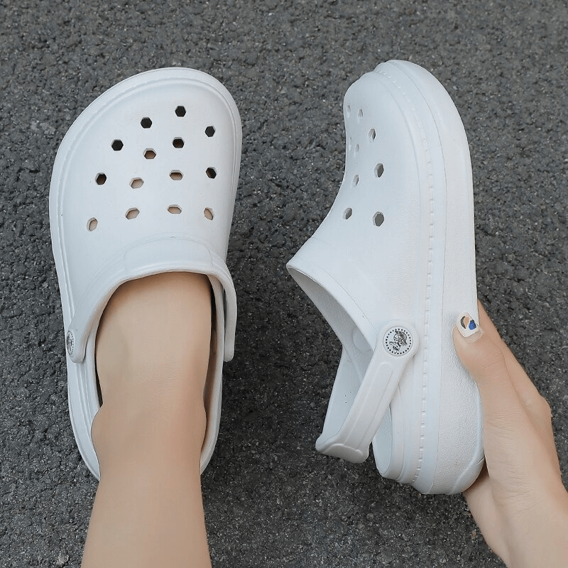 Person wearing stylish flexible lightweight unisex white Crocs, showcasing superior comfort and slip-on ease against a textured background.