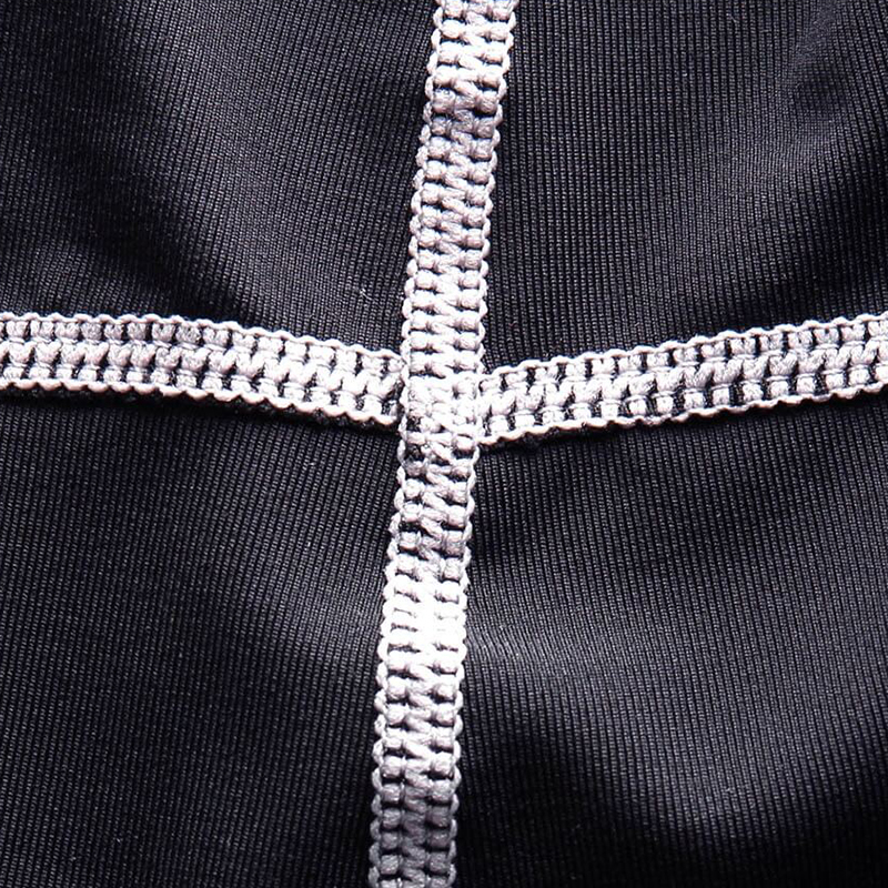 Close-up of black compression sports top fabric with white cross-stitch detailing for durability and style.